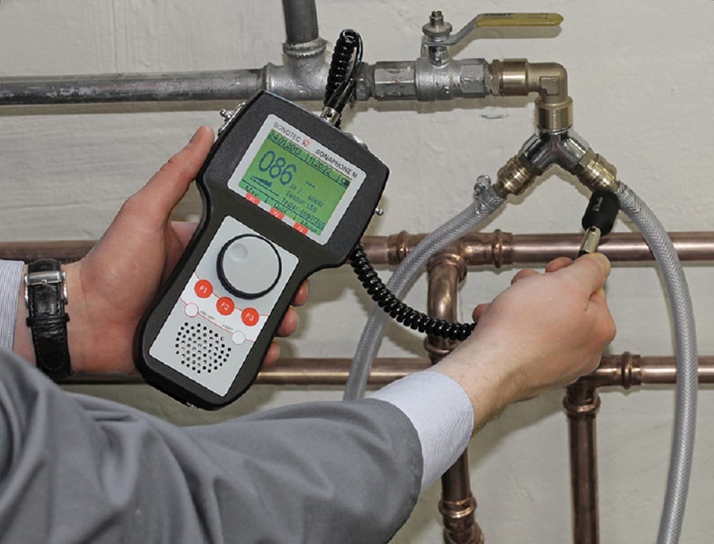 Plumber testing pipes with electronic leak detection equipment in Brighton