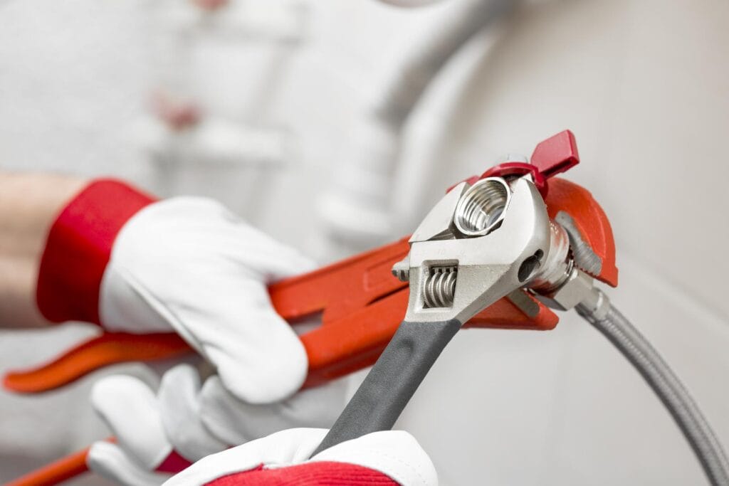 Plumber holding pipe wrenches for an emergency repair in Brighton