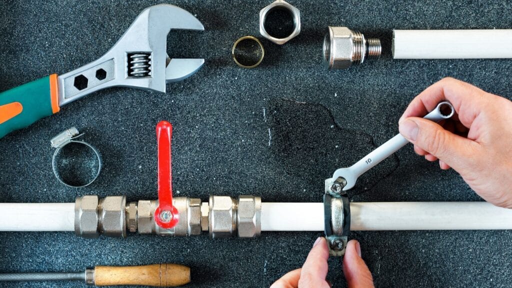 Plumber repairing a pipe valve with an adjustable wrench in Brighton