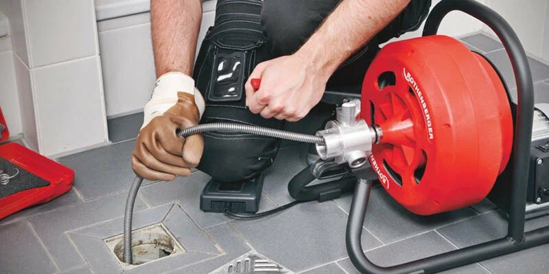 Plumber using a drain-cleaning machine in Brighton