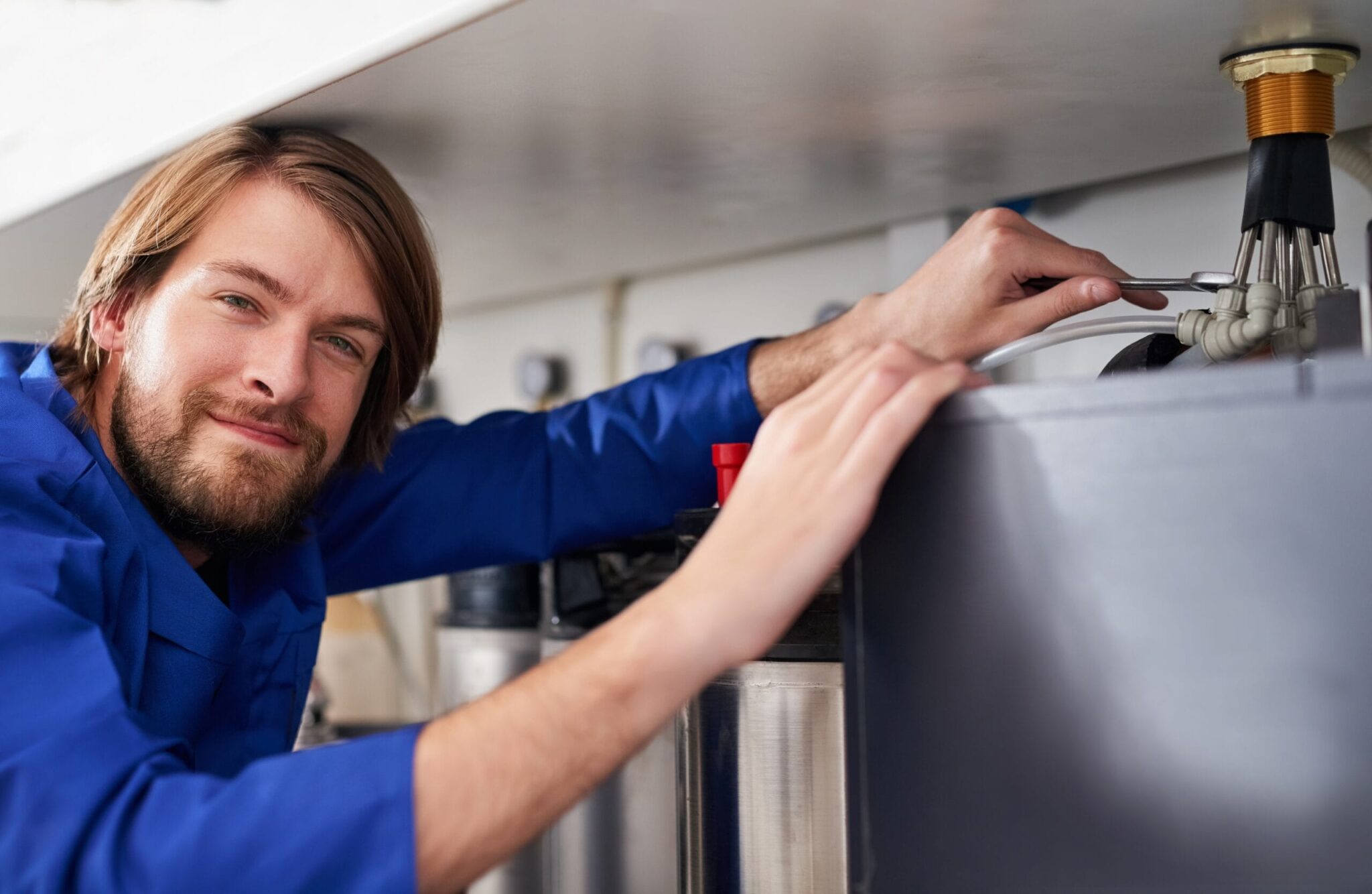 Technician servicing a residential water heater tank in Brighton