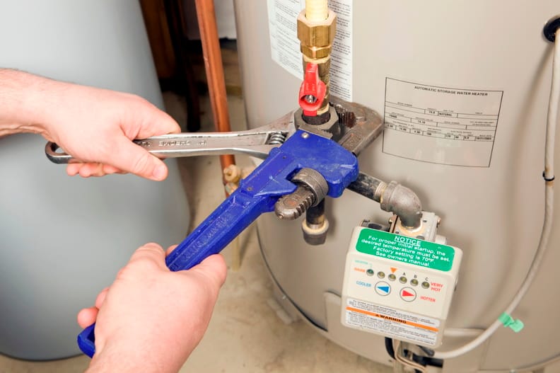 Plumber repairing a water heater valve in Brighton